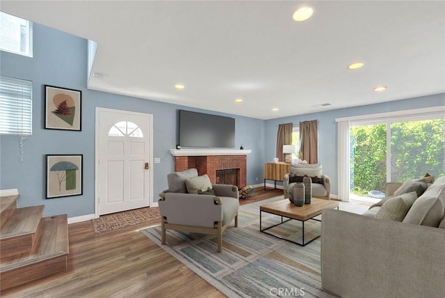 living room with wood finished floors, baseboards, plenty of natural light, recessed lighting, and a brick fireplace