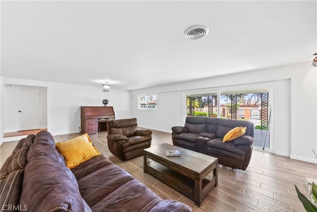 living area featuring visible vents, baseboards, and wood finished floors