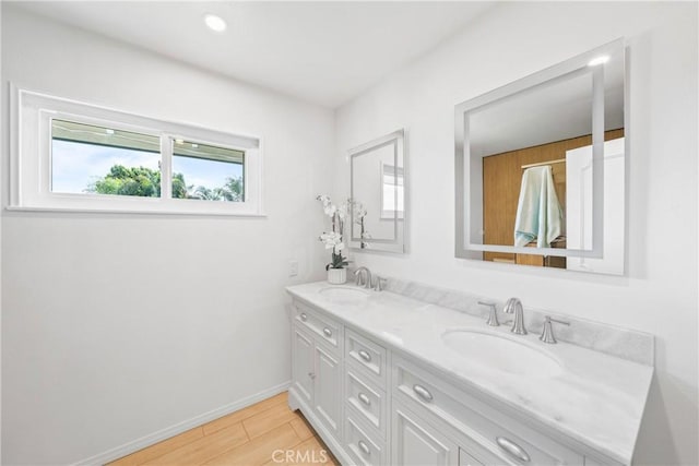 full bath with double vanity, a sink, and baseboards