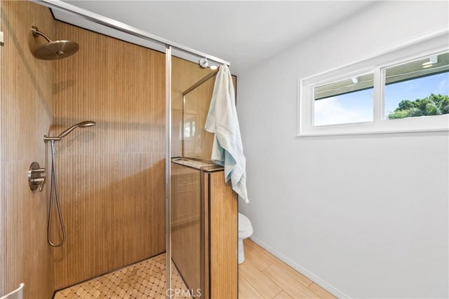 full bath featuring toilet, a shower stall, and baseboards