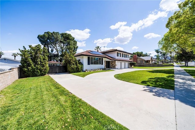 view of front of house with a garage, stucco siding, fence, solar panels, and concrete driveway