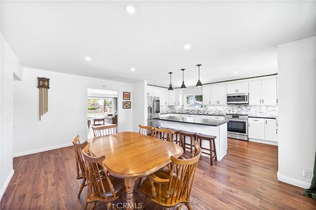 dining room with dark wood-type flooring, baseboards, and recessed lighting