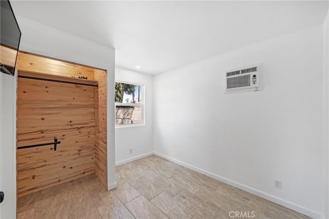 unfurnished bedroom featuring an AC wall unit, baseboards, and recessed lighting