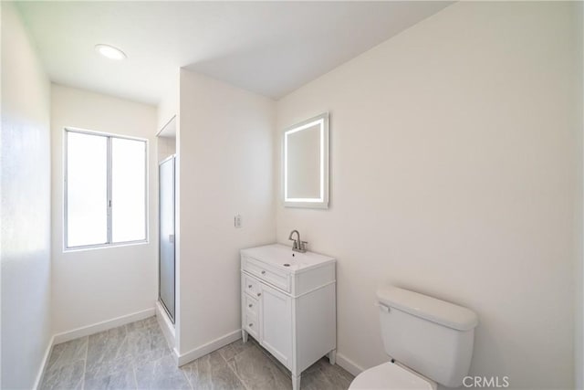 full bath with toilet, a shower stall, vanity, and baseboards