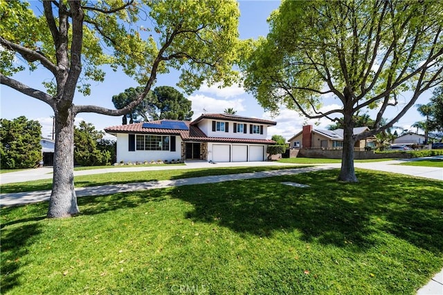 traditional-style home featuring concrete driveway, an attached garage, a front yard, a tiled roof, and roof mounted solar panels