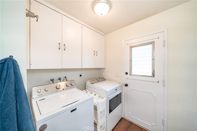 clothes washing area featuring separate washer and dryer, wood finished floors, and cabinet space