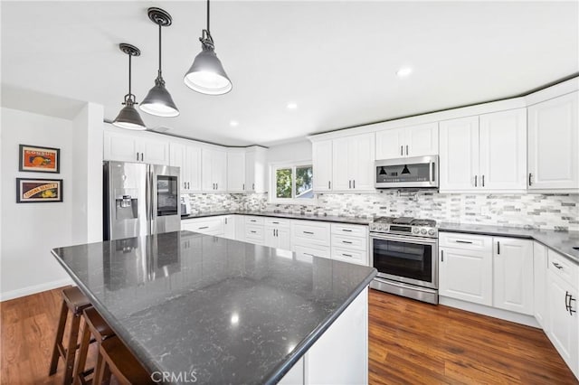 kitchen featuring stainless steel appliances, a kitchen island, dark wood-type flooring, and decorative backsplash