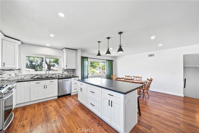 kitchen featuring a sink, a healthy amount of sunlight, dark countertops, and stainless steel appliances