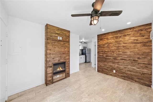 unfurnished living room with a large fireplace, wooden walls, a ceiling fan, and recessed lighting