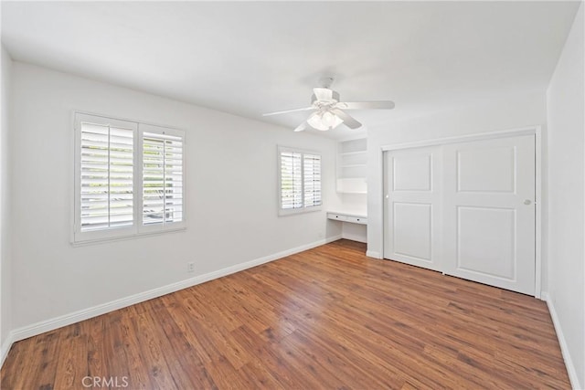 unfurnished bedroom with wood finished floors, ceiling fan, baseboards, and a closet