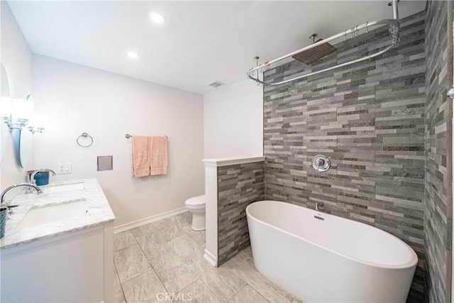bathroom featuring a soaking tub, toilet, a sink, double vanity, and baseboards