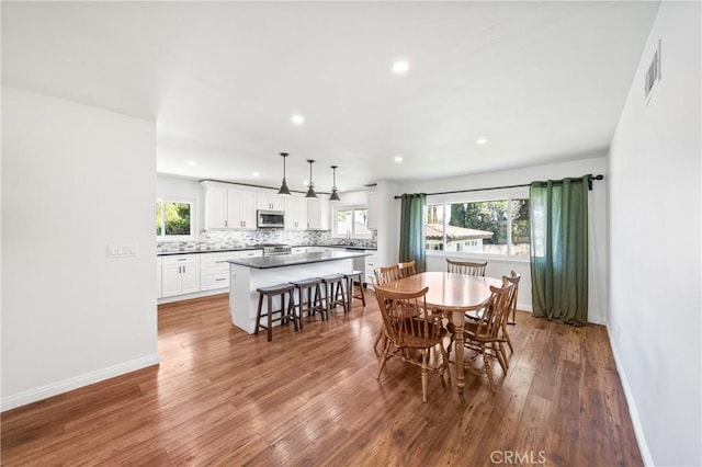 dining space with wood finished floors, baseboards, visible vents, and recessed lighting