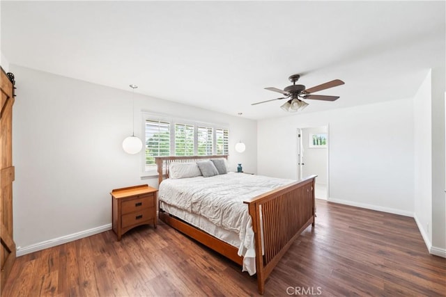 bedroom with a barn door, baseboards, a ceiling fan, and dark wood finished floors