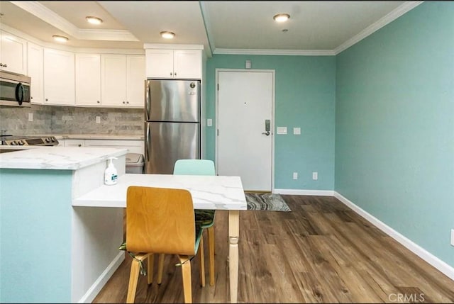 kitchen with white cabinets, crown molding, tasteful backsplash, and stainless steel appliances