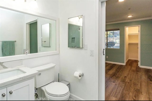 bathroom with wood finished floors, toilet, vanity, crown molding, and baseboards