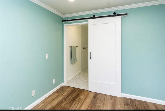 interior space with ornamental molding, a barn door, baseboards, and dark wood-style flooring
