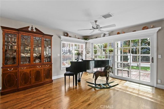living area featuring visible vents, ceiling fan, wood finished floors, and baseboards
