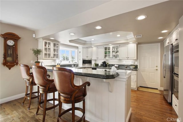 1803 La Cima, San Clemente, CA 92672 - kitchen featuring a tray ceiling, a kitchen breakfast bar, recessed lighting, appliances with stainless steel finishes, and white cabinetry