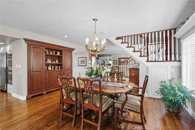 dining area featuring a chandelier, stairway, baseboards, and wood finished floors