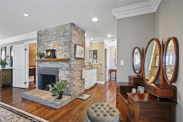 living room featuring crown molding, a fireplace, recessed lighting, wood finished floors, and baseboards