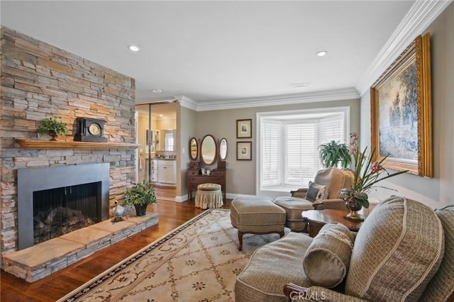 living area featuring baseboards, a stone fireplace, crown molding, recessed lighting, and wood finished floors