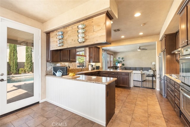 30088 Mauroux Ct, Murrieta, CA 92563 - kitchen featuring light stone counters, a peninsula, open floor plan, ceiling fan, and high end refrigerator