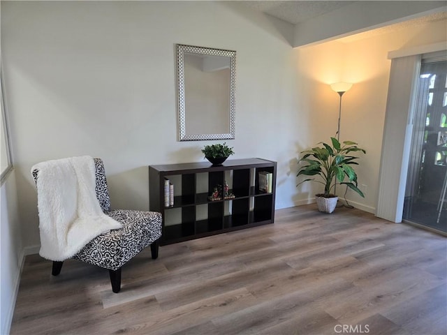 living area with baseboards and wood finished floors