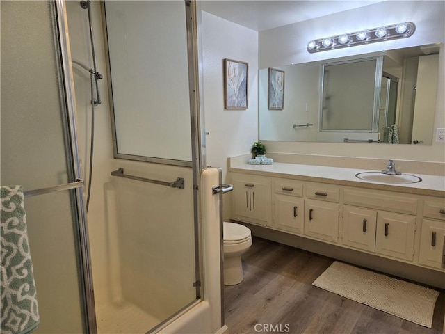 full bathroom featuring wood finished floors, a stall shower, toilet, and vanity
