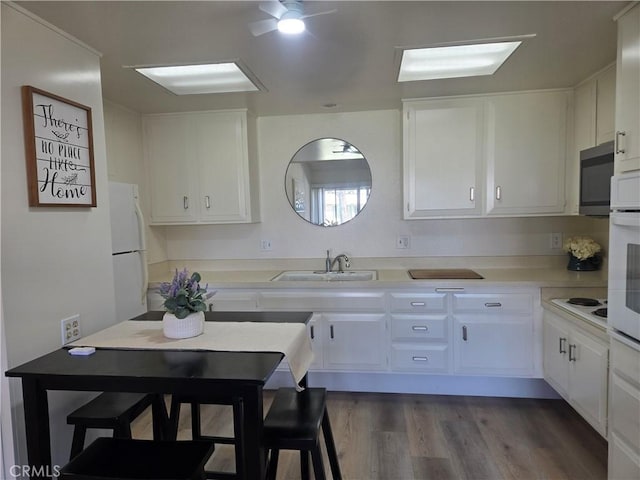 kitchen with light countertops, white cabinets, a sink, and ceiling fan