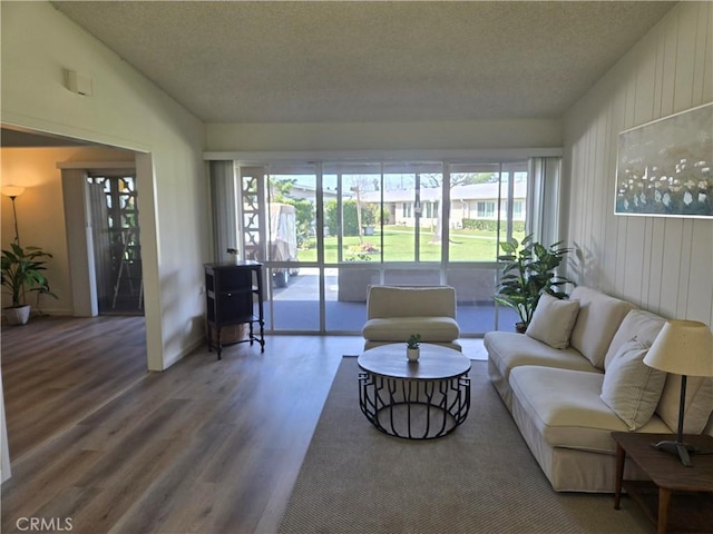 living area featuring wood walls, a textured ceiling, lofted ceiling, and wood finished floors
