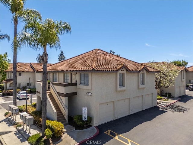 23325 La Crescenta Unit D, Mission Viejo, CA 92691 - view of front facade featuring stairway, stucco siding, an attached garage, a tiled roof, and driveway