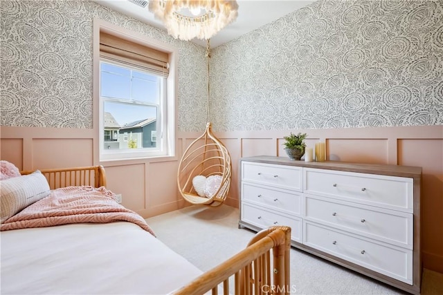 bedroom with a decorative wall, a notable chandelier, wainscoting, and wallpapered walls