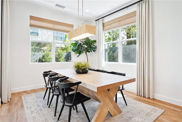 dining room featuring light wood-style floors, plenty of natural light, and visible vents