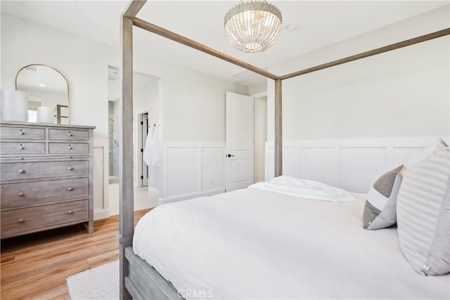 bedroom with a notable chandelier, light wood-style flooring, and a wainscoted wall
