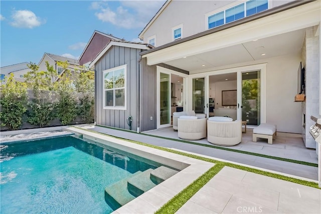 rear view of property with a fenced in pool, a patio area, board and batten siding, and fence