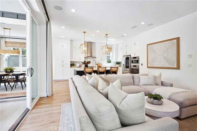 living area with visible vents, light wood finished floors, and recessed lighting