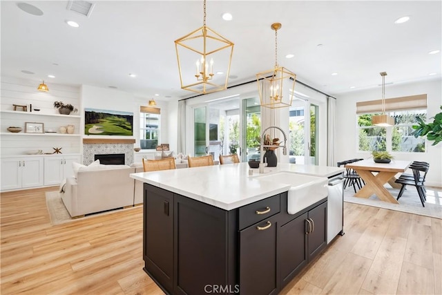 kitchen with light wood-type flooring, visible vents, a chandelier, a healthy amount of sunlight, and a sink
