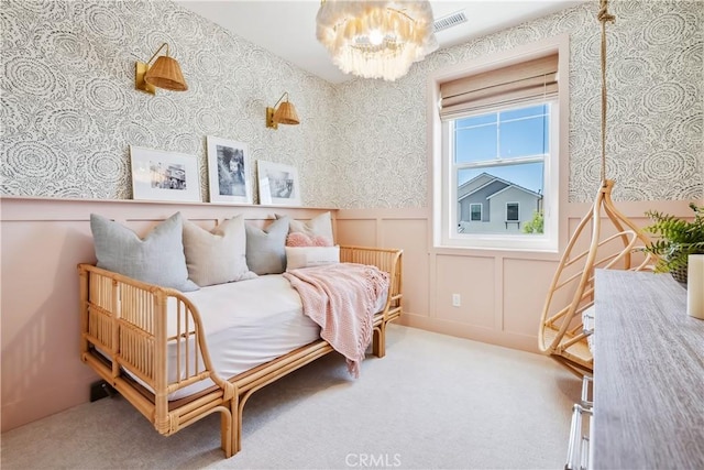 bedroom featuring visible vents, a chandelier, carpet floors, wainscoting, and wallpapered walls