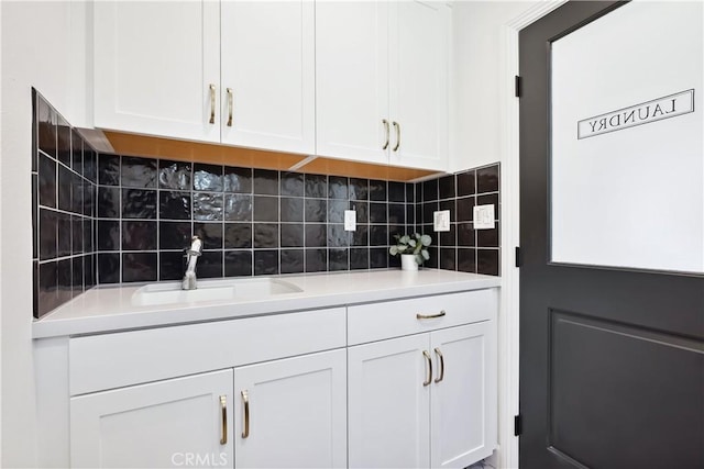 interior space with white cabinets, tasteful backsplash, light countertops, and a sink