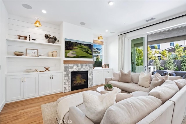 living area featuring recessed lighting, a fireplace, light wood finished floors, and visible vents