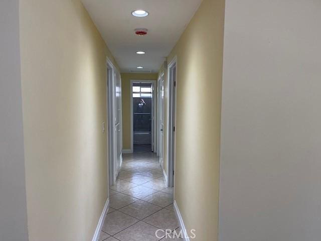 hall with baseboards, recessed lighting, and light tile patterned flooring