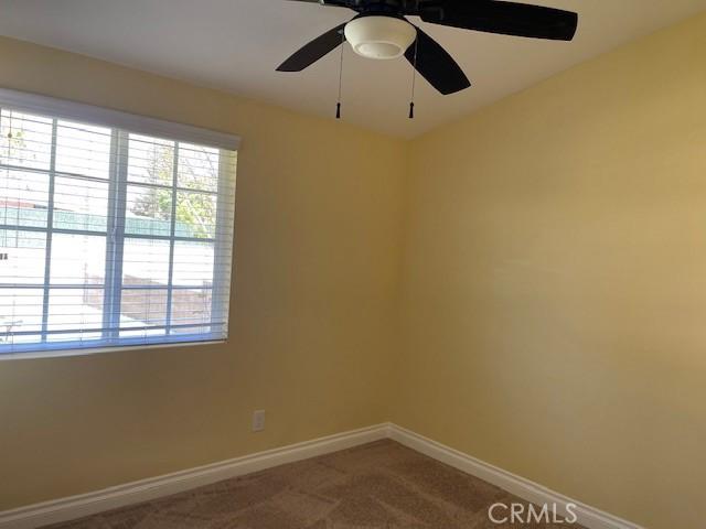 unfurnished room with ceiling fan, baseboards, and carpet flooring