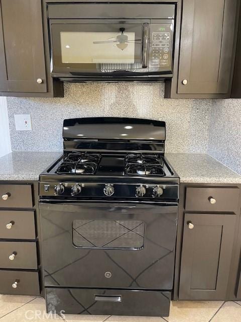 kitchen featuring gray cabinetry, tasteful backsplash, light tile patterned floors, and black appliances
