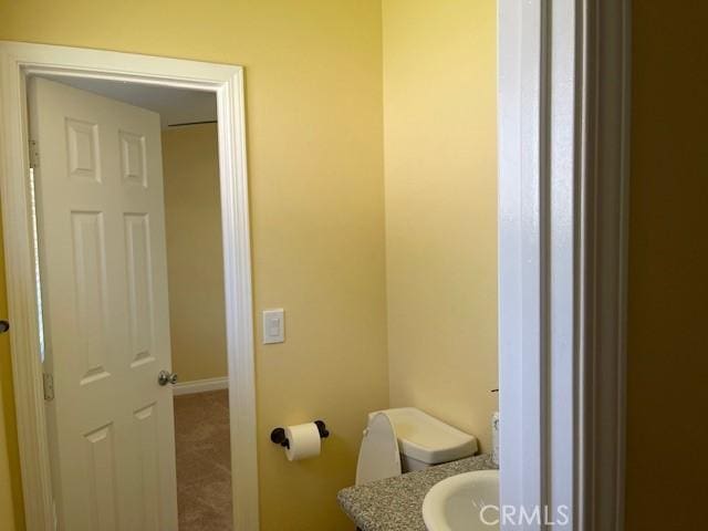 bathroom with toilet, vanity, and baseboards