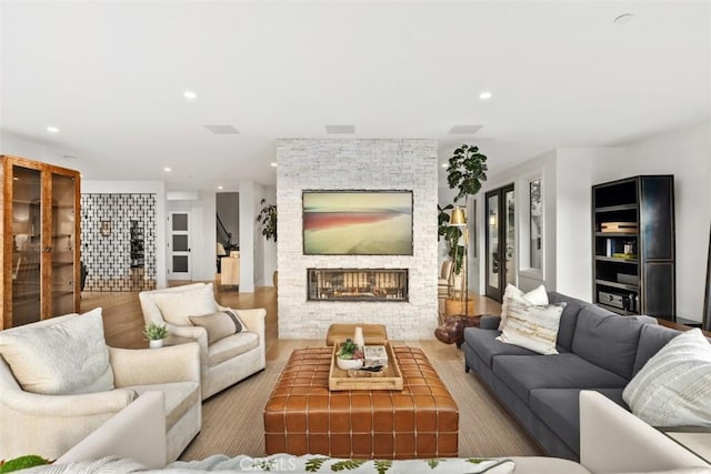 living area with recessed lighting, a stone fireplace, and wood finished floors
