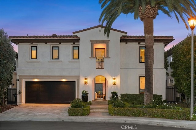 mediterranean / spanish-style house with a tiled roof, a garage, stucco siding, and driveway