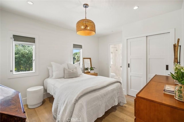 bedroom with ensuite bathroom, light wood-style flooring, multiple windows, and recessed lighting