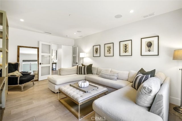 living room featuring light wood finished floors, visible vents, and recessed lighting