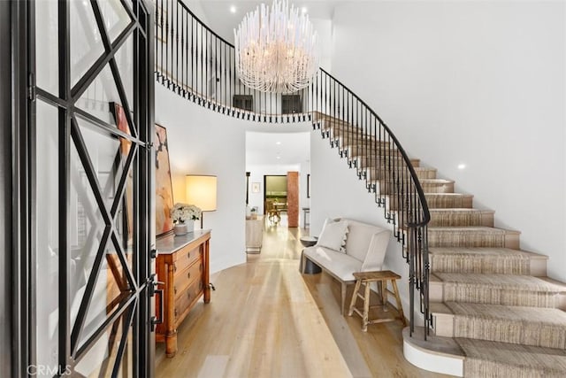 foyer with a high ceiling, light wood-style flooring, an inviting chandelier, and stairs