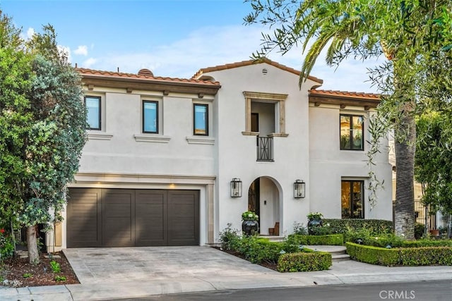 mediterranean / spanish-style home with a tile roof, a garage, driveway, and stucco siding